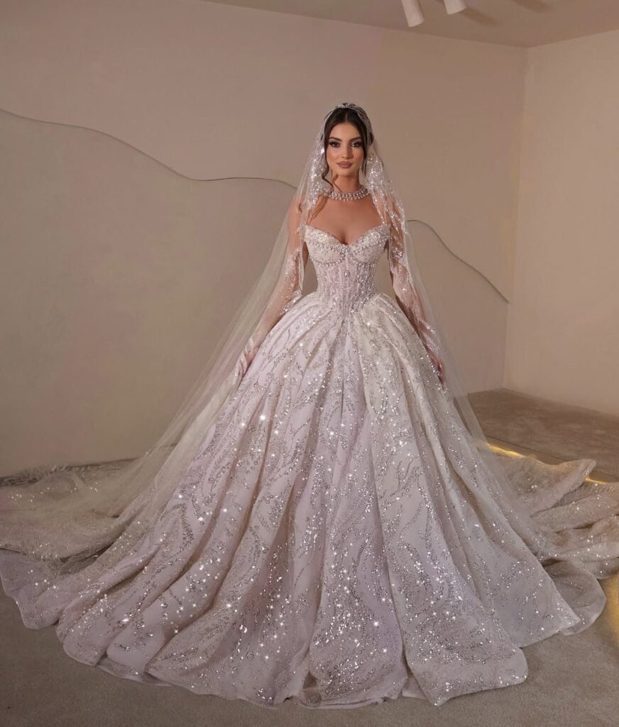 Woman wearing a sparkling white ballgown wedding dress and a long sheer veil.