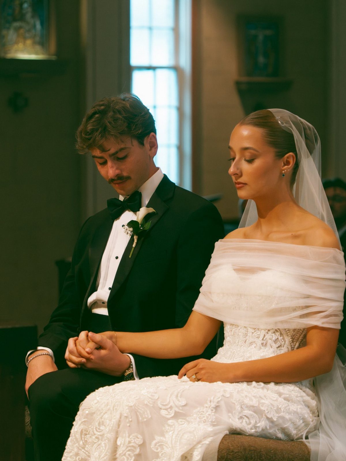 A bride and groom sitting together and holding hands during their wedding ceremony.