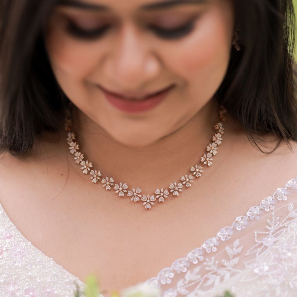 A woman wearing a sparkling floral-patterned necklace with a white lace neckline.